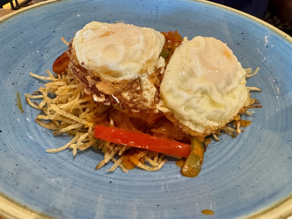 Huevos Bulla featuring fried eggs over crispy shoestring potatoes and peppers at Bulla Gastrobar in Downtown Doral, Florida