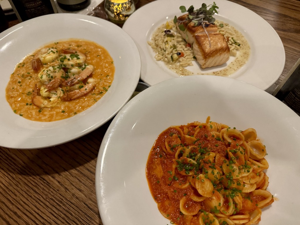 Three gourmet seafood and pasta dishes including shrimp risotto, grilled fish with orzo, and orecchiette pasta at Citrus Grillhouse in Vero Beach, Florida