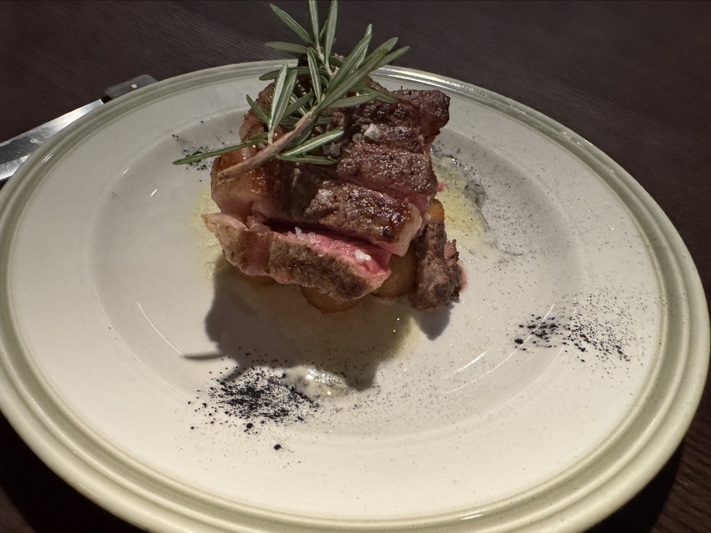 Grilled sliced steak garnished with fresh rosemary sprig and sea salt on a ceramic plate at Hereford Grill in Miami, Florida