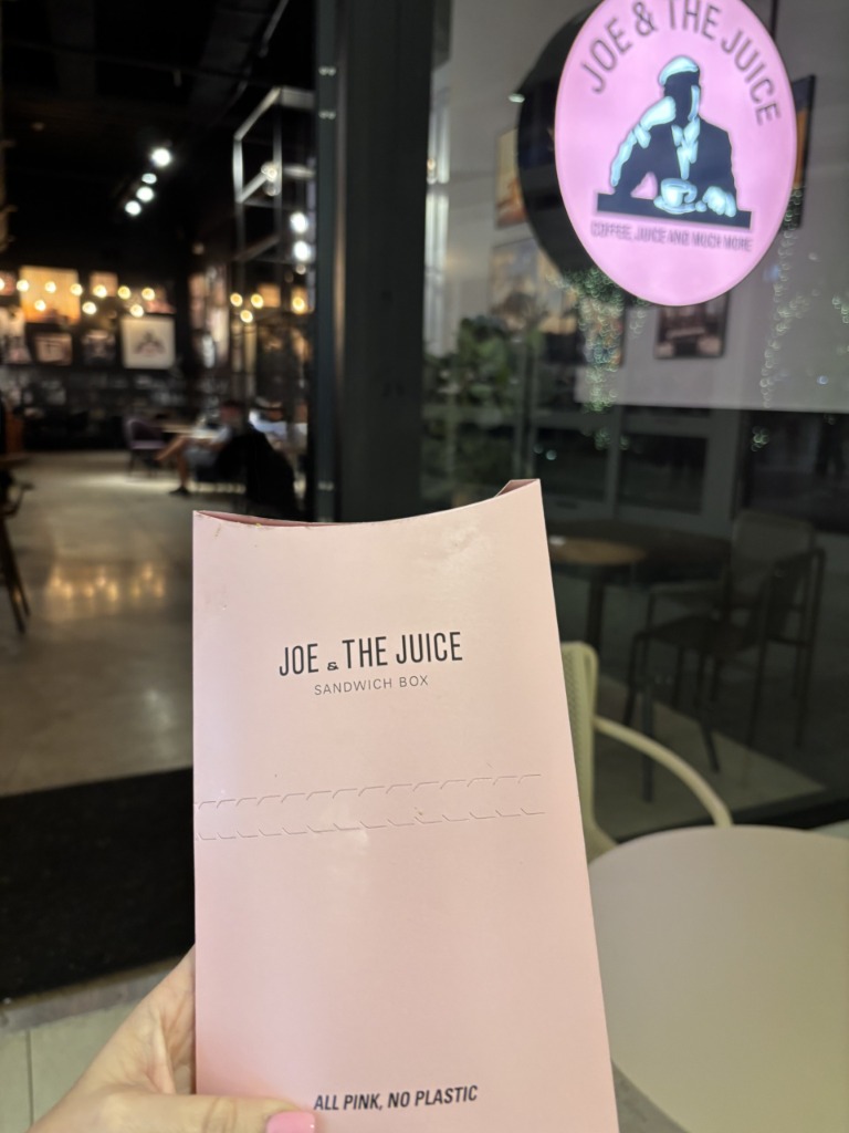 Signature pink sandwich box in front of the Joe & The Juice store