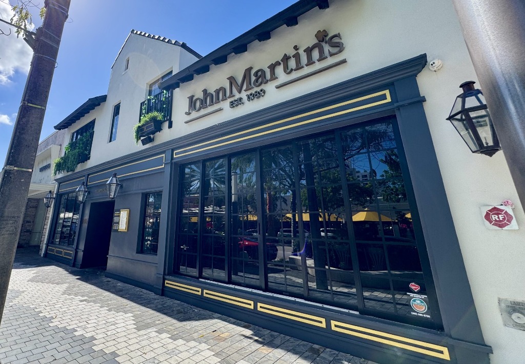Modern painted grey exterior storefront with large windows of Johnmartin's Restaurant & Bar on Miracle Mile in Coral Gables, Florida