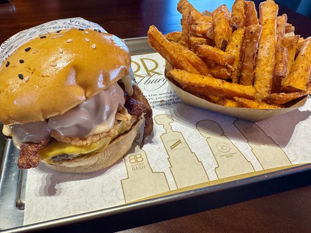 Award-winning gourmet burger with crispy bacon and melted cheese served alongside sweet potato fries at La Birra Bar in Weston, Florida