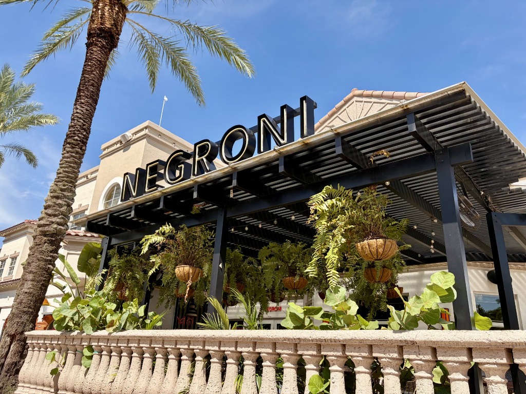 Chic wooden pergola terrace and lush hanging ferns exterior at Negroni Bistro & Sushi Bar in Weston Town Center, Florida