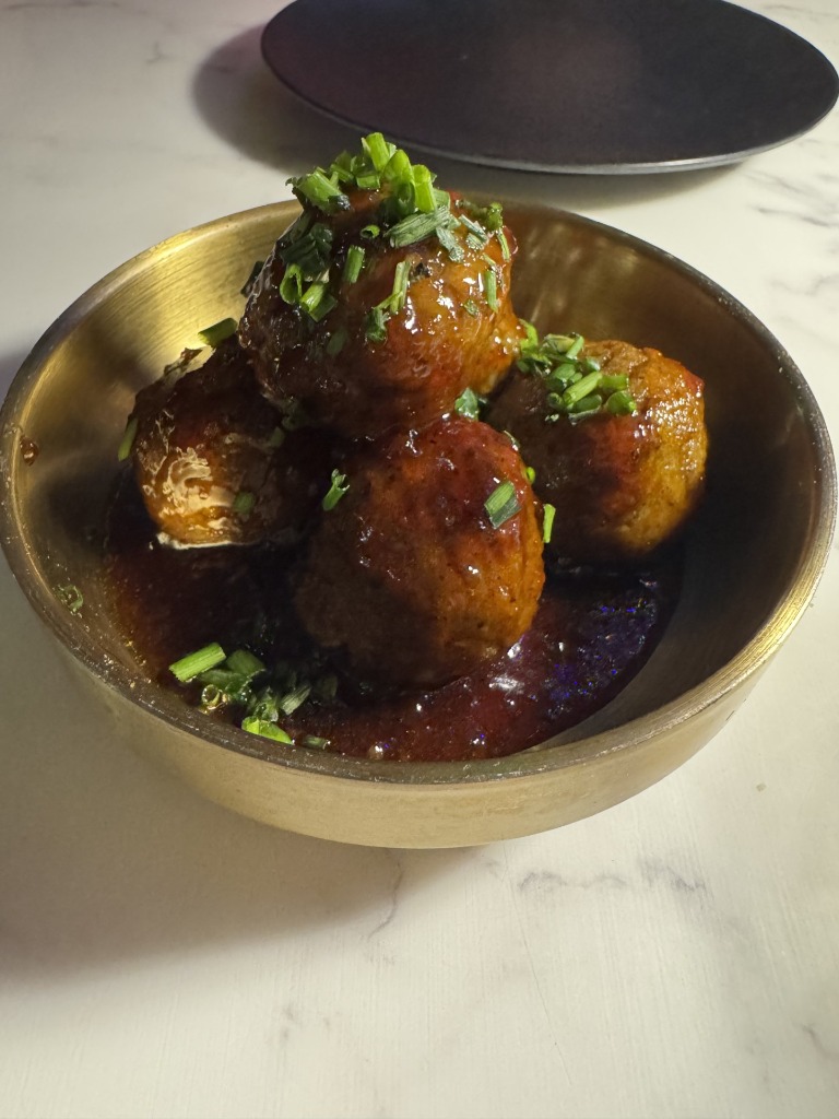 Savory Italian meatballs in red marinara sauce with chives at Rosalia's Kitchen in Miramar, Florida