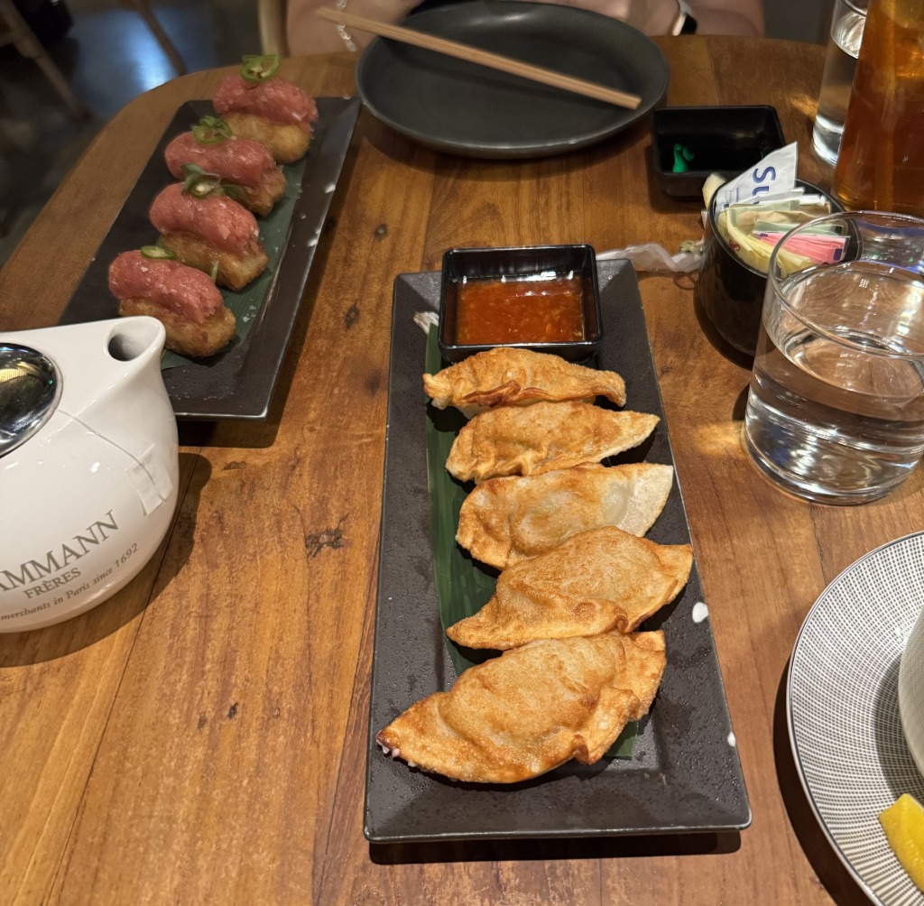 Fried gyoza dumplings and crispy rice sushi on black slate platters at Tanuki River Landing in Miami, Florida